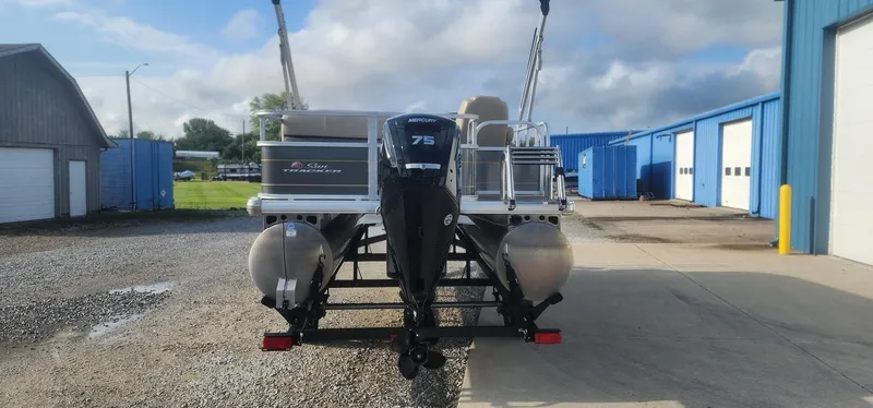 Slide: The Image of 2024 Sun Tracker Party Barge 18 DLX pontoon boat with Mercury 75 engine, parked outdoors. - 4