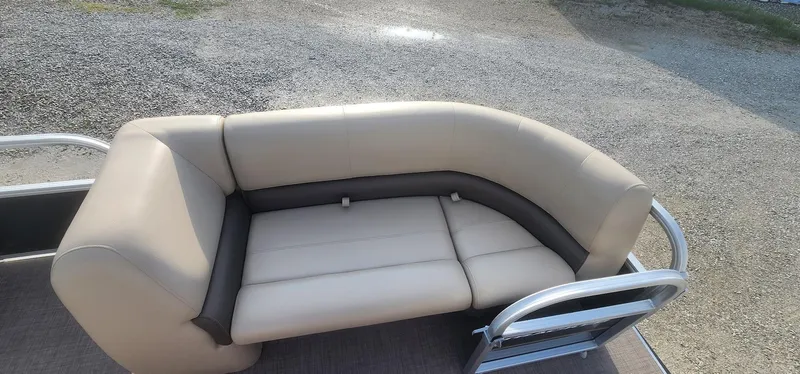 Slide: The Image of 2024 Sun Tracker Party Barge 18 DLX with beige and gray seating on gravel background. - 9