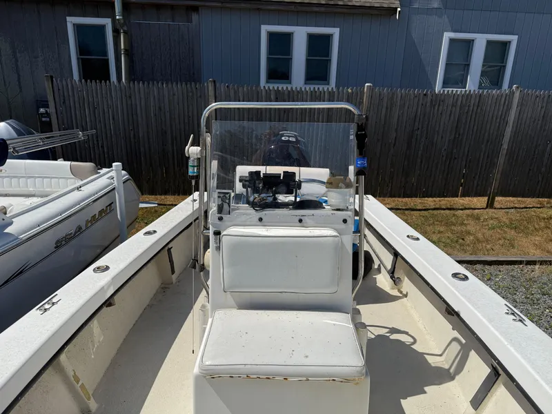 Slide: The Image of 1998 C-Hawk 18 boat interior with console and seating, parked beside a wooden fence. - 6
