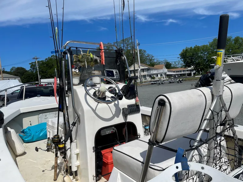 Slide: The Image of 1998 C-Hawk 18 boat with fishing gear, steering console, and seating, docked under a clear blue sky. - 7