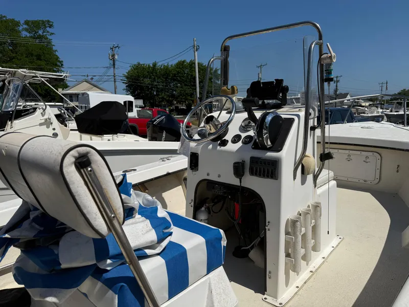 Slide: The Image of 1998 C-Hawk 18 boat interior with steering console and seating, docked under clear blue sky. - 8