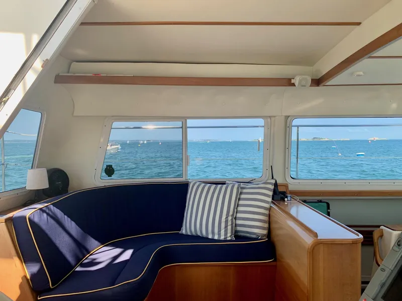 Slide: The Image of Interior of 2003 PDQ-34 boat with wooden cabinetry, blue seating, and nautical decor. - 10