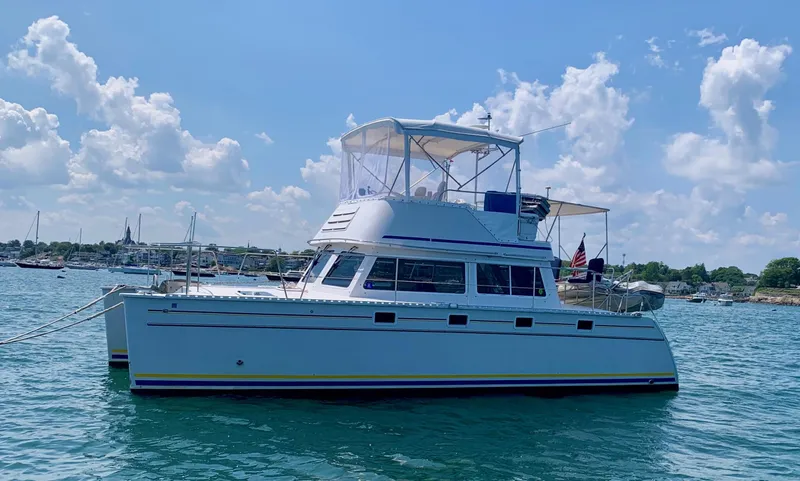 Slide: The Image of 2003 PDQ-34 catamaran "Tranquility Base" on calm blue water under clear sky. - 2
