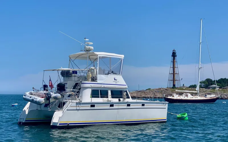 Slide: The Image of 2003 PDQ-34 catamaran anchored on calm water under a clear blue sky. - 3