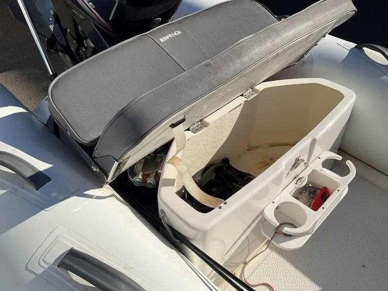 Slide: The Image of Open storage compartment on 2016 Brig F330HT boat with cup holders and accessories. - 15