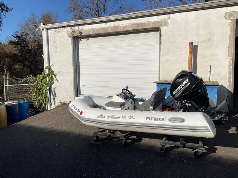 Slide: The Image of 2016 Brig F330HT inflatable boat with Mercury engine, parked outside a garage. - 4