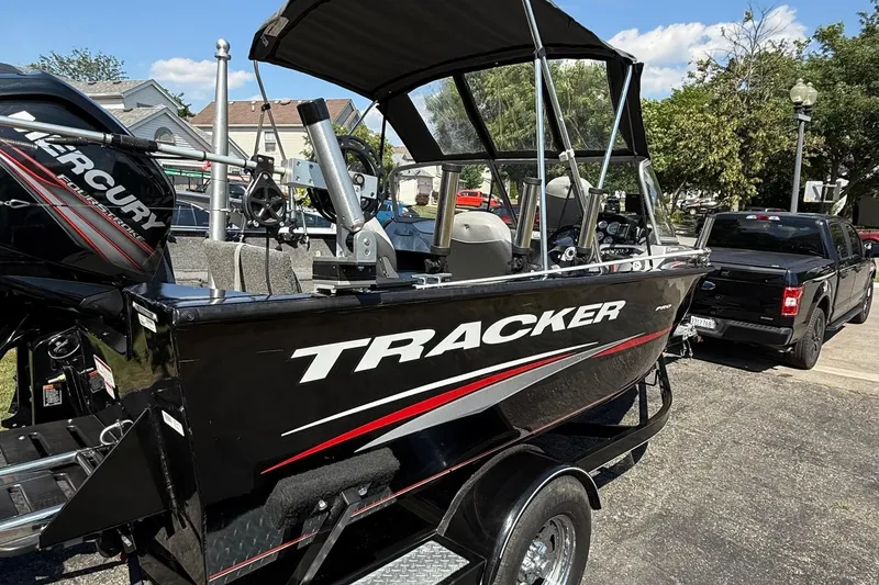 Slide: The Image of 2015 Tracker Pro Guide V-175 WT boat on trailer, parked near black truck. - 2