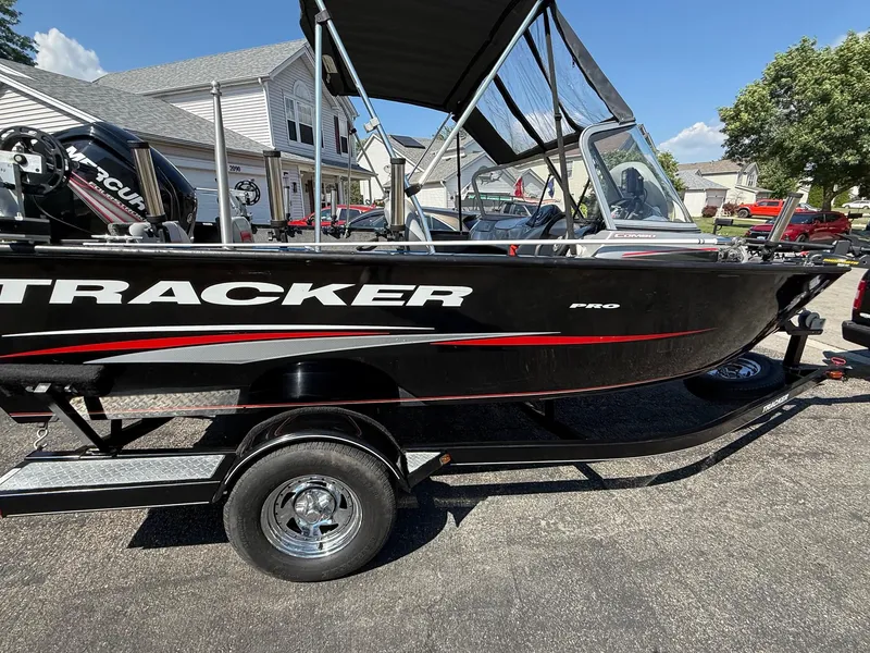 Slide: The Image of 2015 Tracker Pro Guide V-175 WT boat on trailer, black with red accents, parked in residential area. - 3
