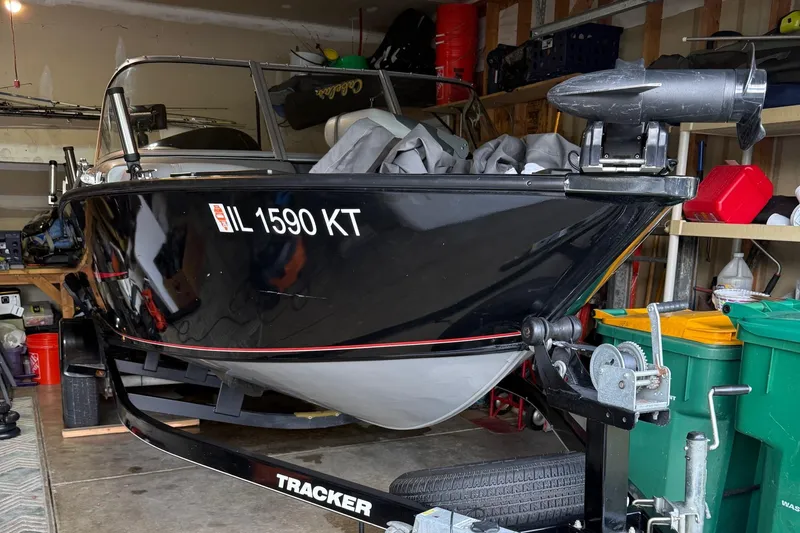 Slide: The Image of 2015 Tracker Pro Guide V-175 WT boat in garage, black hull, trailer visible. - 9