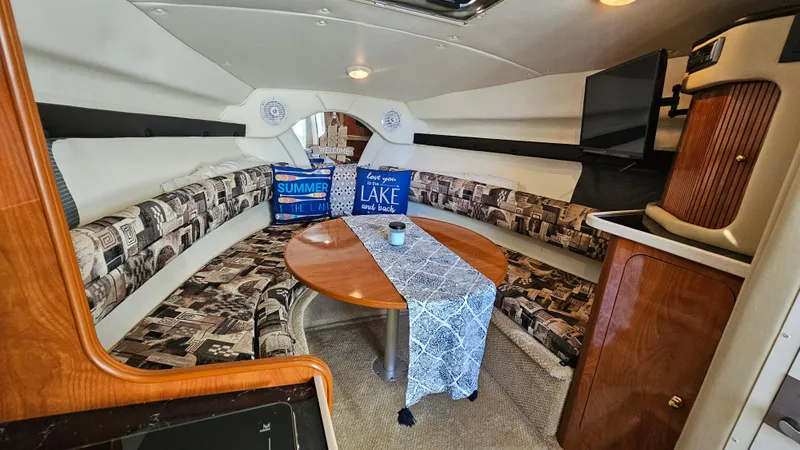 Slide: The Image of 2003 Rinker Fiesta Vee 270 cabin interior with cozy seating, table, and decorative pillows. - 14