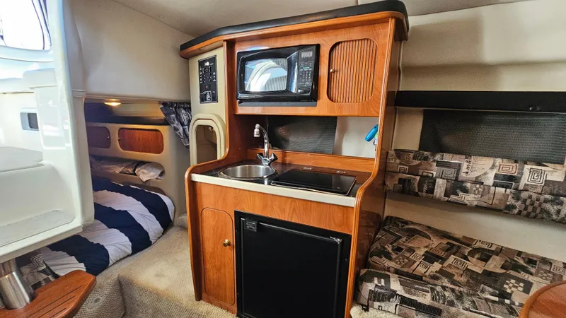 Slide: The Image of 2003 Rinker Fiesta Vee 270 cabin interior with kitchenette, bed, and seating area. - 15