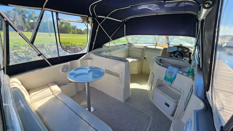 Slide: The Image of 2003 Rinker Fiesta Vee 270 boat interior with seating, table, and helm under canopy. - 5