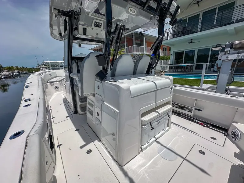 Slide: The Image of 2024 Sea Fox 328 Commander boat interior with seating and storage, docked near waterfront homes. - 13
