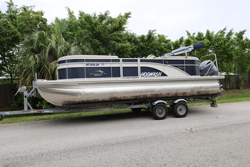 Slide: The Image of 2019 Bennington SX 22 SSXP pontoon boat on trailer, surrounded by greenery. - 0