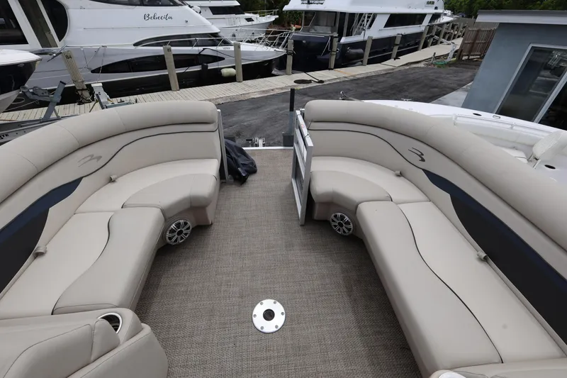 Slide: The Image of 2019 Bennington SX 22 SSXP pontoon boat interior with beige seating and docked yachts. - 17