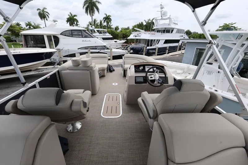 Slide: The Image of 2019 Bennington SX 22 SSXP pontoon boat interior with luxurious seating and helm, docked near yachts. - 18