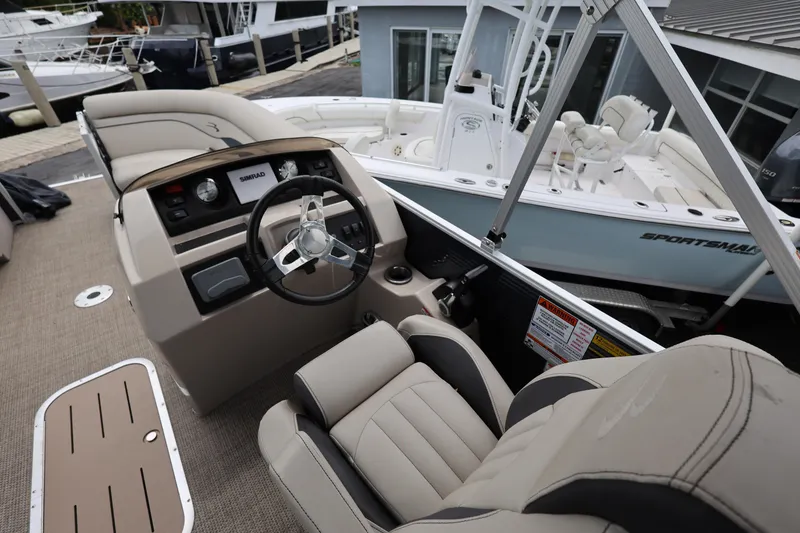 Slide: The Image of 2019 Bennington SX 22 SSXP boat interior with steering wheel and seating at a marina. - 19