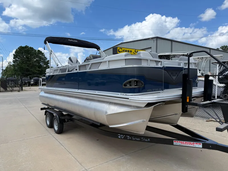 Slide: The Image of 2025 Avalon VENTURE QUAD LOUNGER pontoon boat on trailer, parked outdoors under blue sky. - 2