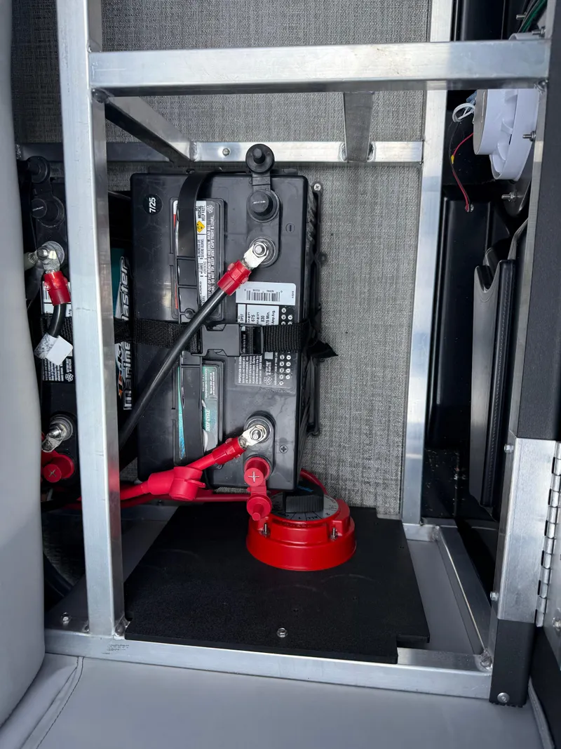 Slide: The Image of Battery compartment of 2025 Avalon Venture Quad Lounger with red cables and secure housing. - 32