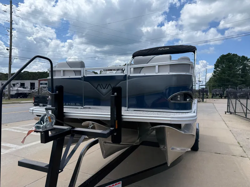 Slide: The Image of 2025 Avalon VENTURE QUAD LOUNGER boat on trailer, parked outdoors under cloudy sky. - 6