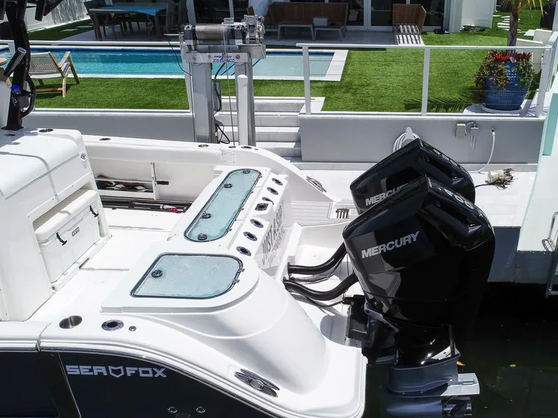 Slide: The Image of 2024 Sea Fox 328 Commander boat with dual Mercury engines docked near a modern poolside. - 11