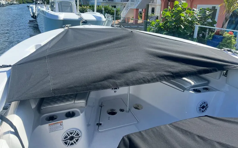Slide: The Image of 2024 Sea Fox 328 Commander boat with black sunshade, docked near lush greenery. - 25