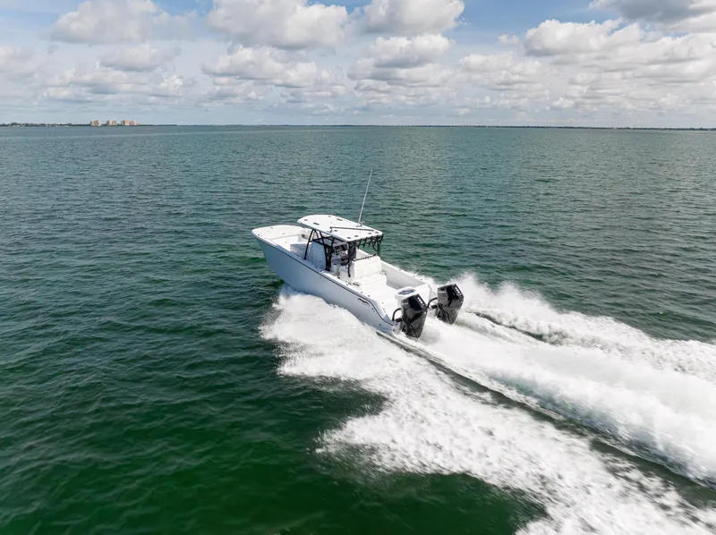 Slide: The Image of 2026 Invincible 33 Catamaran cruising on open water under a cloudy sky. - 2