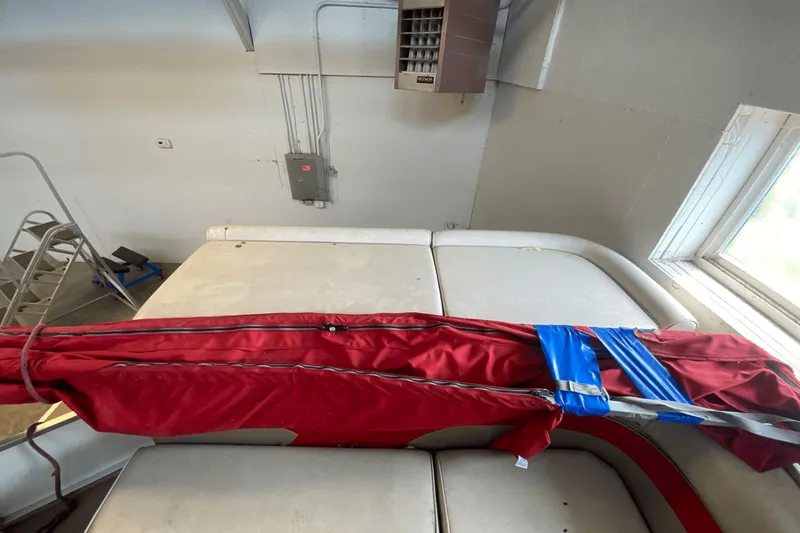 Slide: The Image of 2007 Palm Beach 220 LX boat interior with red cover and blue tape in a garage. - 14