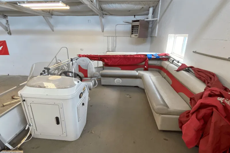 Slide: The Image of 2007 Palm Beach 220 LX boat interior with red and gray seating in a garage. - 4