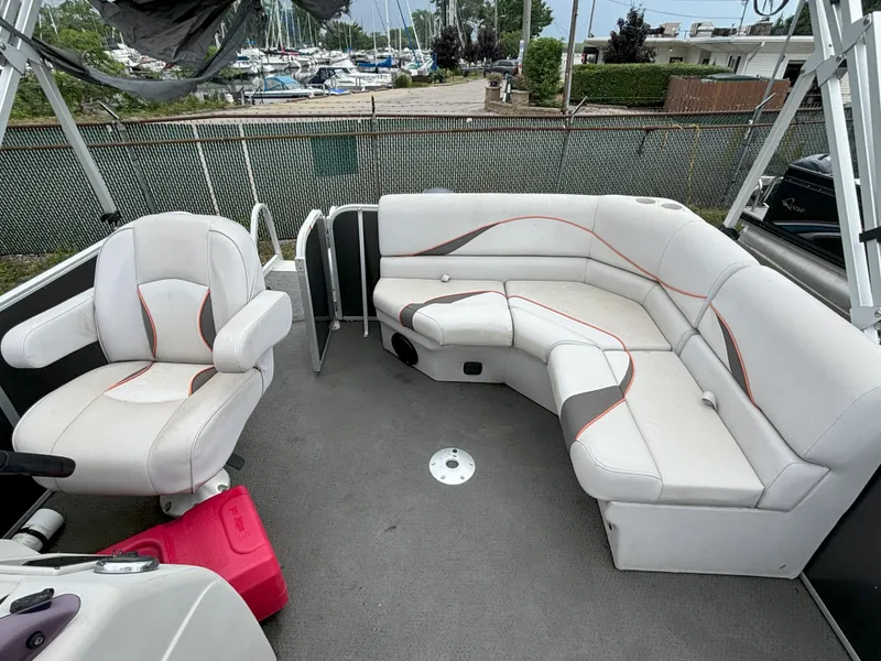 Slide: The Image of 2018 SunCatcher V16 Cruise boat interior with white seating and marina background. - 8