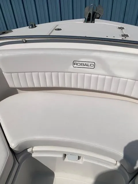 Slide: The Image of 2014 Robalo R247 Dual Console boat seating with logo, white upholstery, and blue background. - 10