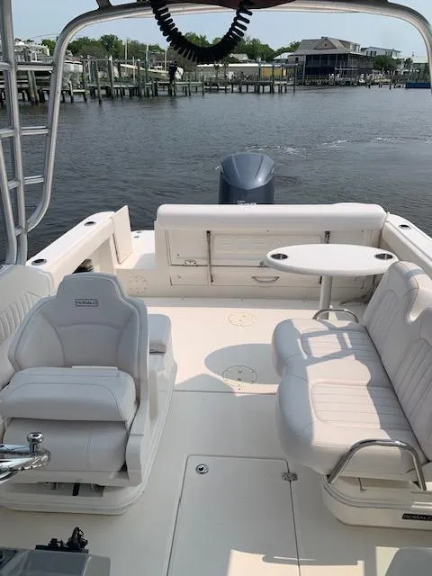 Slide: The Image of 2014 Robalo R247 Dual Console boat interior with seating and table, docked by the water. - 13