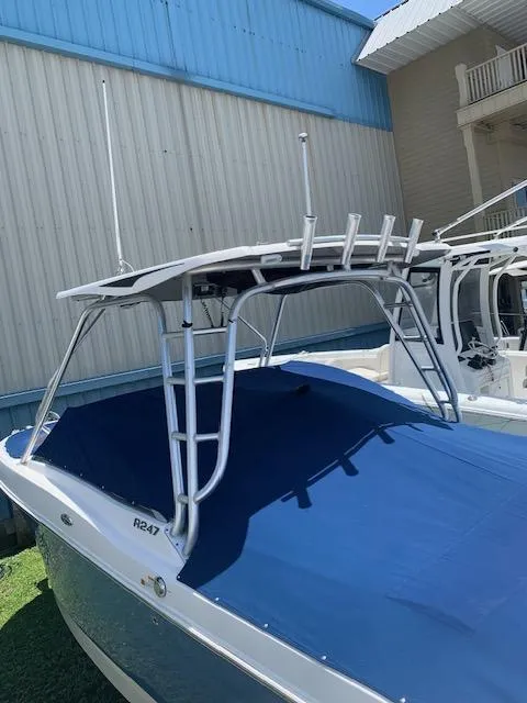 Slide: The Image of 2014 Robalo R247 Dual Console boat with blue cover and T-top, docked outdoors. - 3
