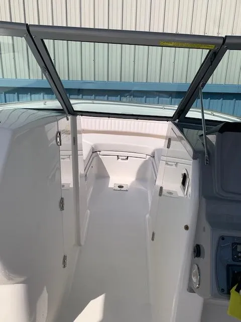 Slide: The Image of 2014 Robalo R247 Dual Console boat interior with open windshield, white seating, and storage compartments. - 9