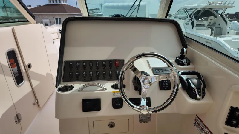 Slide: The Image of 2026 Grady-White Freedom 325 boat helm with steering wheel and control panel. - 13