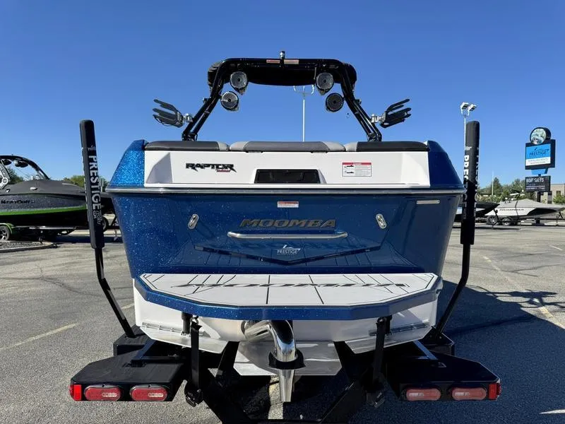 Slide: The Image of 2020 Moomba Max boat rear view, blue and white, parked outdoors on a sunny day. - 4