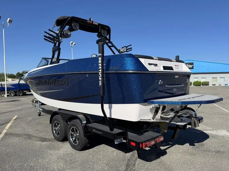 Slide: The Image of 2020 Moomba Max boat on trailer, blue and white, parked in a lot under clear sky. - 9