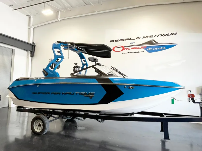 The Image of 2020 Nautique G21 boat in showroom, blue and black design, on trailer. - 1