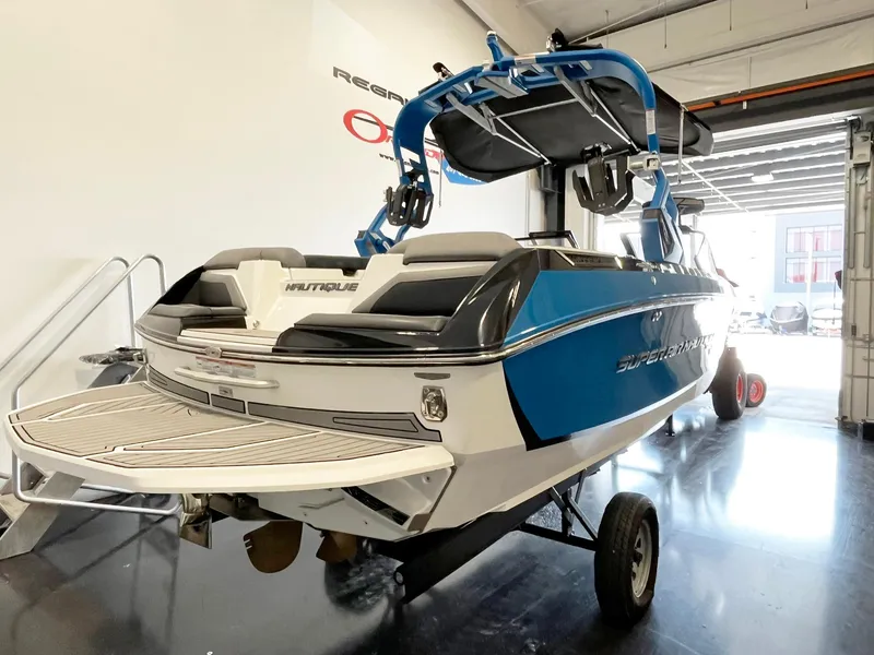 Slide: The Image of 2020 Nautique G21 boat in showroom, blue and white design, on trailer. - 4
