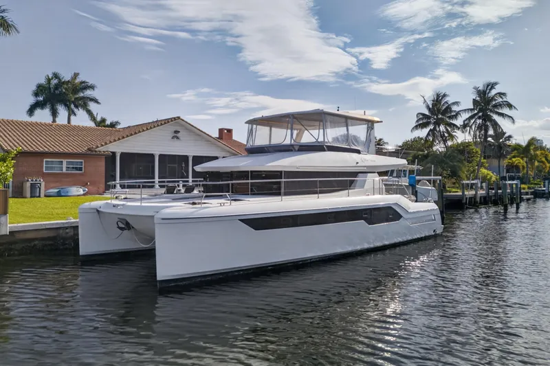 The Image of 2022 Leopard 53 Powercat yacht docked by waterfront homes, surrounded by palm trees. - 0