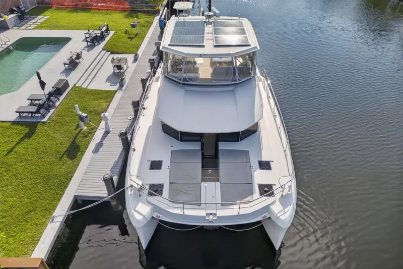 Slide: The Image of 2022 Leopard 53 Powercat yacht docked by a poolside, showcasing sleek design and solar panels. - 10