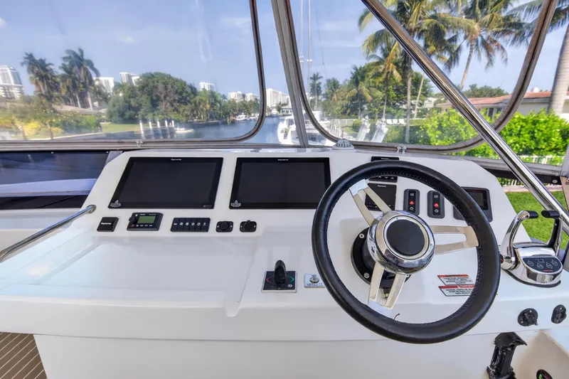 Slide: The Image of 2022 Leopard 53 Powercat helm with dual screens and steering wheel, surrounded by lush scenery. - 14