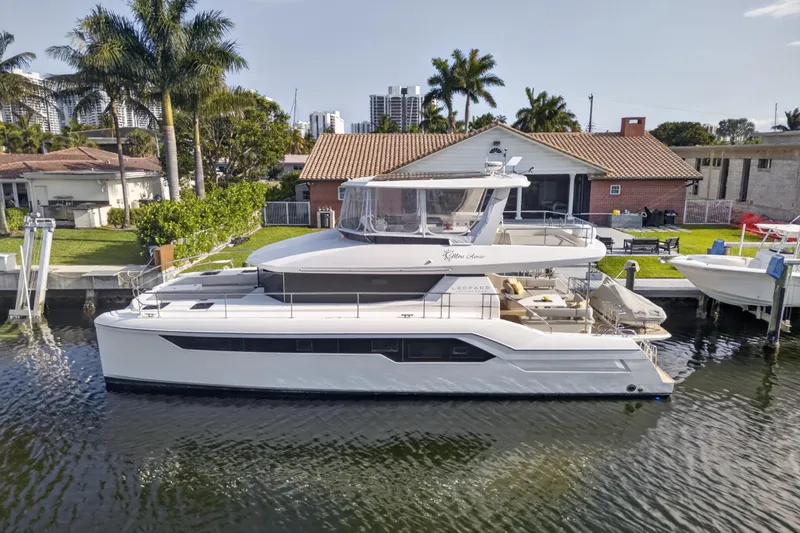 Slide: The Image of 2022 Leopard 53 Powercat yacht docked by a waterfront home with palm trees. - 3