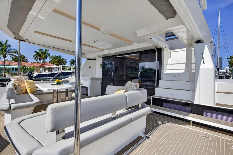 Slide: The Image of 2022 Leopard 53 Powercat yacht deck with seating, table, and stairs, docked in a marina. - 30