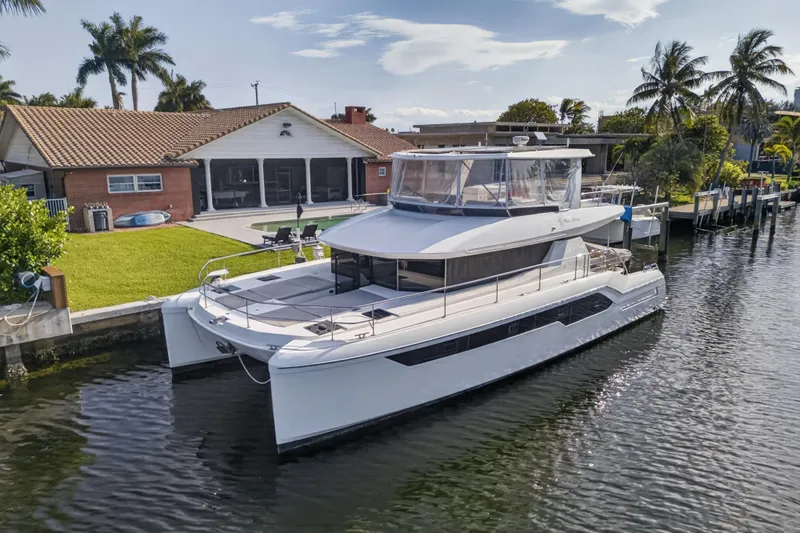 Slide: The Image of 2022 Leopard 53 Powercat yacht docked by a waterfront home with palm trees. - 4
