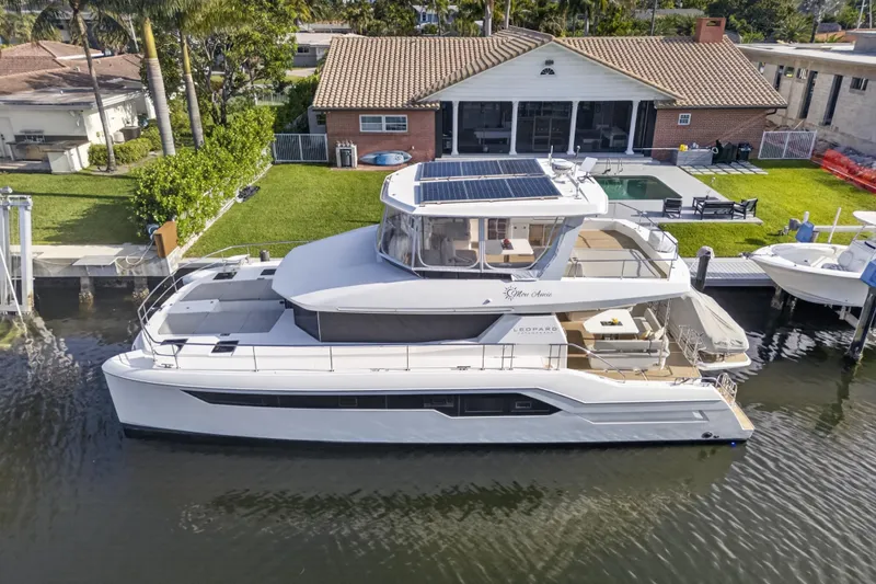 Slide: The Image of 2022 Leopard 53 Powercat yacht docked by a waterfront home. - 6