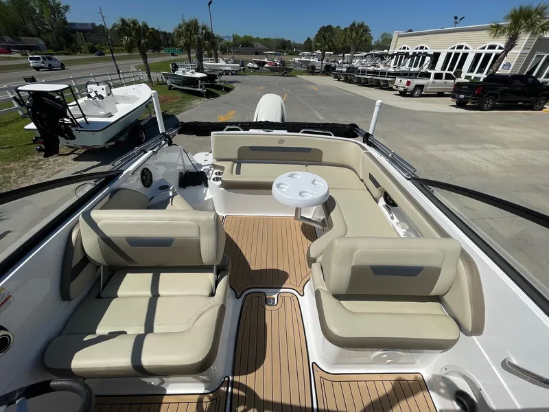 Slide: The Image of 2020 Hurricane SD235 boat interior with beige seating and a round table, parked outdoors. - 11