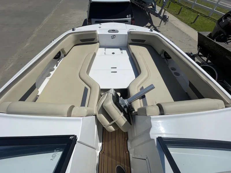 Slide: The Image of 2020 Hurricane SD235 boat interior with beige seating and steering wheel, docked on a sunny day. - 14