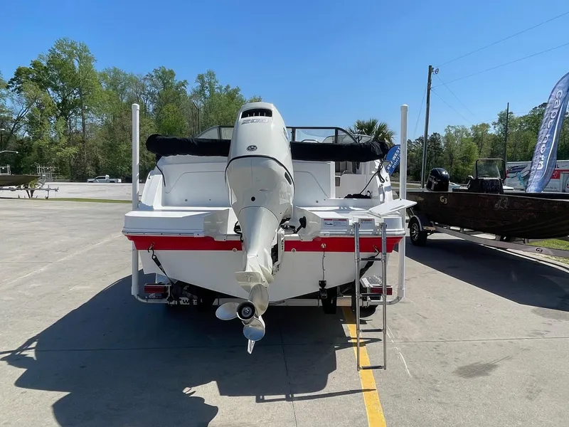 Slide: The Image of 2020 Hurricane SD235 boat with outboard motor, parked on concrete, surrounded by trees and other boats. - 2