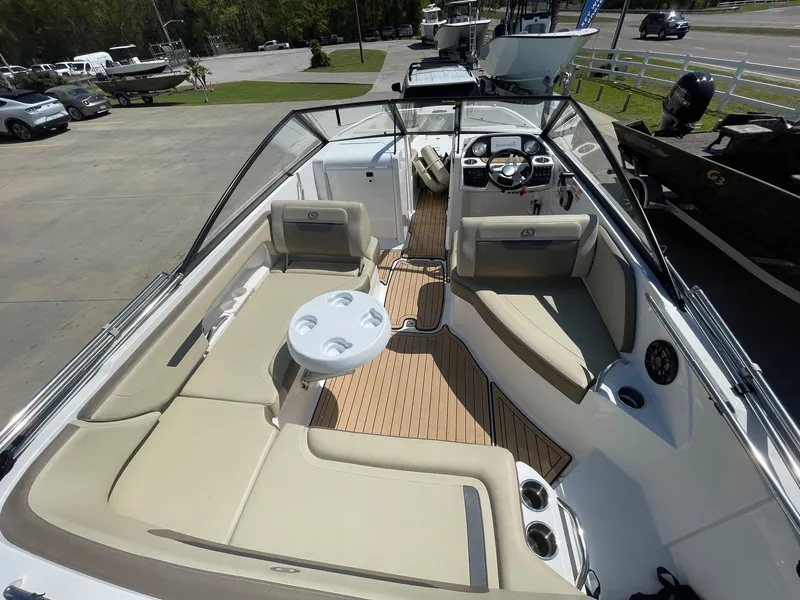 Slide: The Image of 2020 Hurricane SD235 boat interior with beige seating and wood flooring, parked outdoors. - 4
